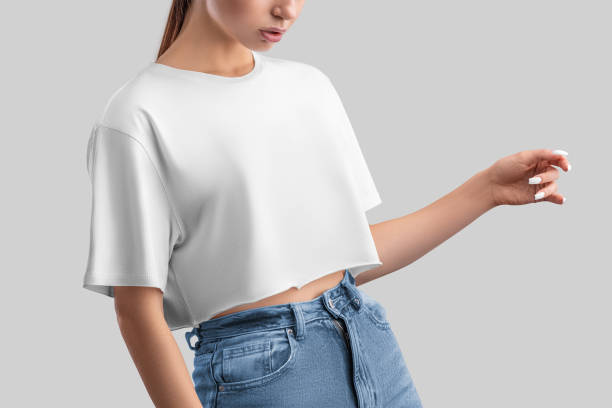 A young woman wearing a casual crop top paired with high-waisted jeans, showing off a playful and versatile fashion choice.