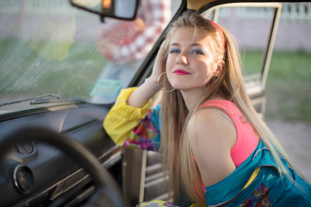 Beautiful girls in the style of the 90s in bright clothes in the salon of the car.