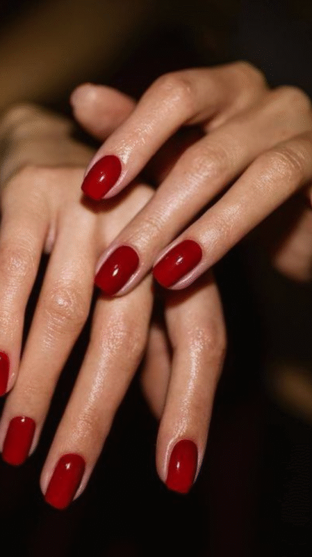 Hand resting on a white table, showcasing bold red nails